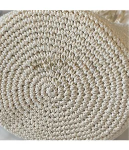 Macro shot showing circular spiral weave pattern on the bottom of a cream straw bucket bag
