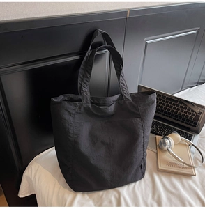 Detailed view of black nylon tote bag showing its large capacity and convenient side pocket