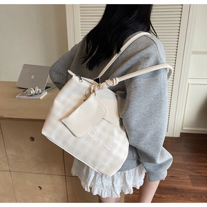 Detail of cream checkered tote bag with knot shoulder strap and mini coin pouch accessory