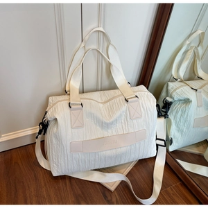 Detail of the large canvas tote bag showing wavy pleated texture and branded leather patch