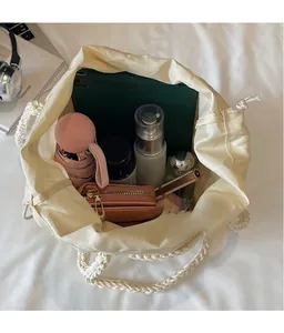 Close-up of cream woven bucket bag showing large capacity for tablet, umbrella, and wallet