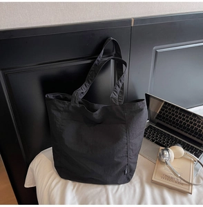 Detailed macro shot of the black waterproof nylon tote bag showing fabric texture and pocket
