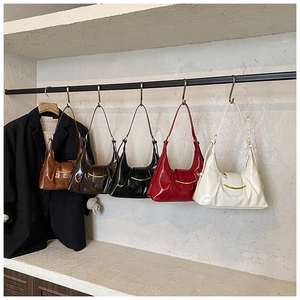 Détail de cinq sacs bandoulière demi-lune en cuir brillant avec ornements dorés