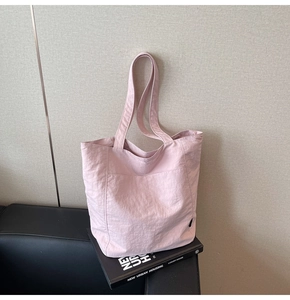 Close-up of a light pink nylon tote bag with crinkled texture on a modern sofa set