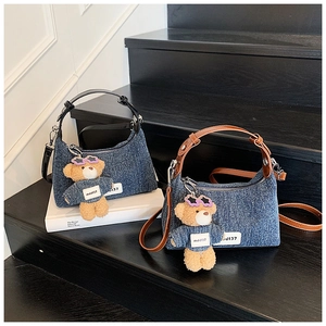 Détail du sac en jean avec charme d'ours en peluche et étiquette J137 sur bois noir