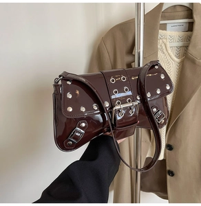 Detail of dark brown patent leather shoulder bag with silver studs and eyelet elements