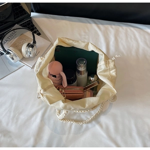 Interior view showing large capacity of beige woven bucket bag with various daily essentials