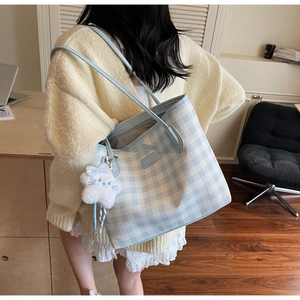 Detail view of blue and white checkered tote bag featuring a cute plush cat charm