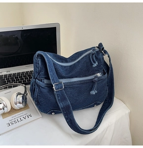 Macro detail of dark blue denim tote bag with multiple zippers and silver rivets