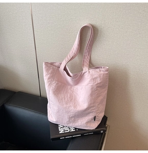 Detail showing the light pink textured nylon tote bag with long shoulder strap
