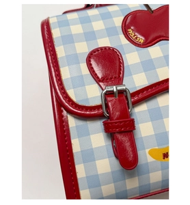 Dettaglio della borsa a quadretti blu e bianchi con ricamo ciliegia e tracolla rossa