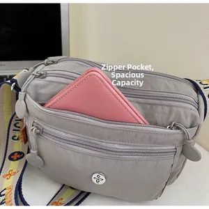 Detail view of grey nylon crossbody bag showing large capacity with three zipper pockets