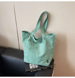 Detail of mint green tote bag featuring a front pocket and high-density nylon texture
