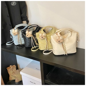 Detail showing four textured bucket bags with cute bear charms and tassel accents