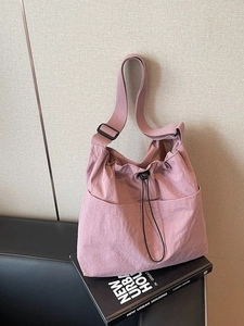 Minimalist dusky pink nylon bucket bag with adjustable wide strap for daily commute