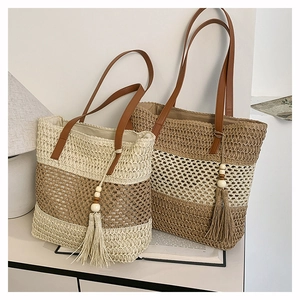 Dettaglio di due borse tote in paglia a righe con tracolle in pelle e nappine decorative