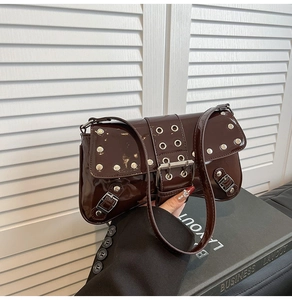 Close-up of dark brown patent leather shoulder bag with silver rivets and buckle detail