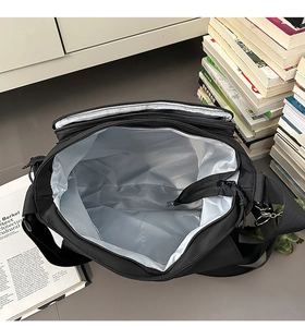 Internal view of black messenger bag showing silver lining and secure zipper pocket