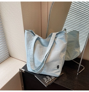 Detail of light blue tote bag featuring pleated texture fabric and minimalist black tag