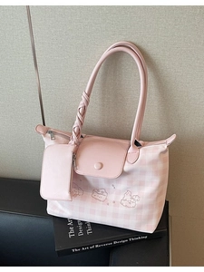 Pink plaid embroidered tote bag with a mini pouch on a black book in a stylish scene