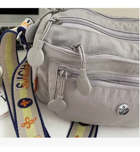 Detail view of Oxford cloth crossbody bag with multi-layer zippers and jacquard strap