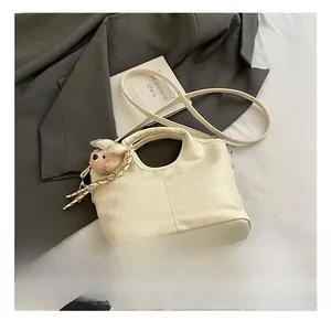 Close-up of cream crocodile pattern handbag featuring a cute brown plush bear charm