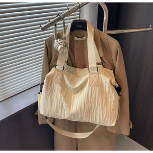 Detailed texture of cream-white large capacity tote bag hung with a brown trench coat