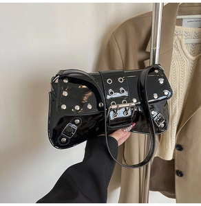 Detalle del bolso de hombro en charol negro con remaches y hebilla metálica