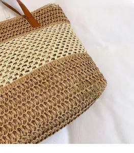 Dettaglio della borsa tote in paglia intrecciata con strisce kaki e manici in pelle