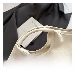 Detailed close-up of cream crocodile pattern leather handbag with precision stitching