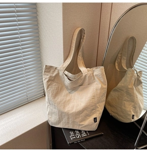 Detail of off-white oversized tote bag showing wrinkled nylon texture and side logo tag
