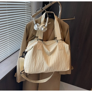 Detail shot of a large pleated canvas tote bag with adjustable straps in a lifestyle scene