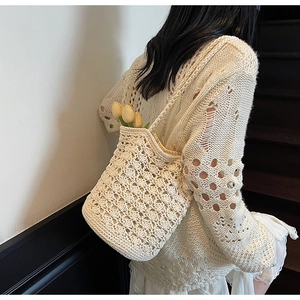 Detail view of cream white hand-woven straw bucket bag with floral crochet pattern