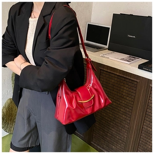 Détail du sac hobo rouge en cuir brillant avec un fermoir en métal doré en demi-lune