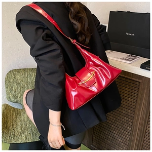 Détail du sac croissant en cuir verni rouge avec boucle dorée sur un mannequin femme