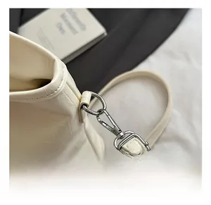 Detail of silver metal hook and crocodile embossed texture on a cream bucket bag