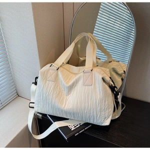 Close-up of pleated cream canvas tote bag showing detailed texture and adjustable strap