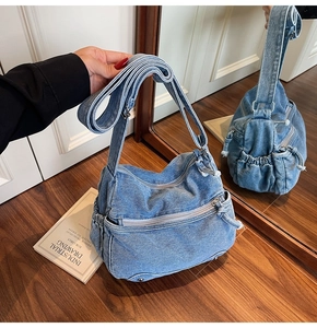 Detail view of denim hobo bag with multiple zipper pockets and adjustable side drawstrings