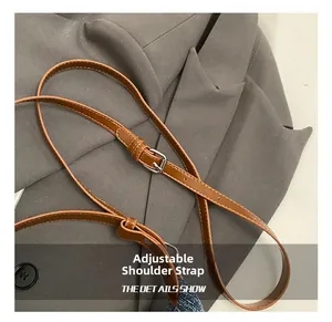 Détail de la bandoulière réglable en similicuir marron avec boucle argentée du sac