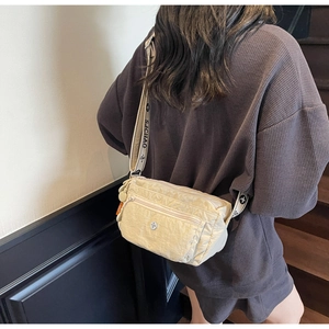 Detail view of beige nylon crossbody bag with adjustable SJCHAO strap on female model