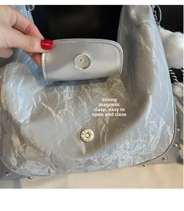 Détail du sac argenté montrant la boucle magnétique puissante et le décor de rivets en métal