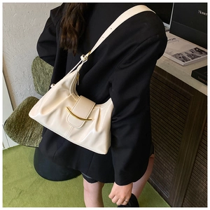 Détail du sac à bandoulière plissé crème avec boucle en croissant doré sur blazer