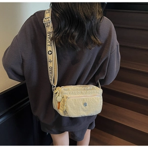 Detail of a beige oxford cloth crossbody bag showing wide patterned SJCHAO shoulder strap