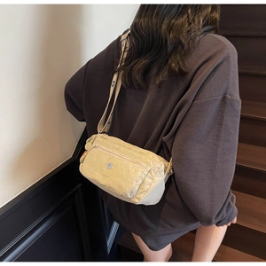 Detail of beige nylon crossbody bag with multiple zip pockets and adjustable strap