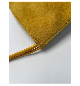 Macro shot of mustard yellow faux suede texture and precise stitching on bucket bag