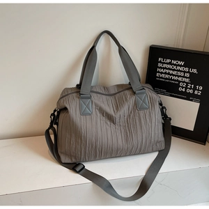 Detail view of the textured pleats and adjustable shoulder strap on the canvas tote bag