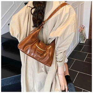 Détail du sac à bandoulière demi-lune marron caramel en cuir brillant avec boucle dorée