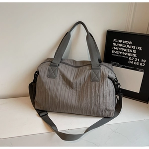 Detail of grey pleated canvas tote bag showing wide nylon handles and adjustable strap