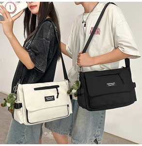 Detail view of canvas messenger bags in black and beige with dinosaur pendant and flap design