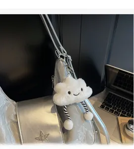 Détail d'un pendentif nuage en peluche blanc avec visage souriant sur un sac à main argenté
